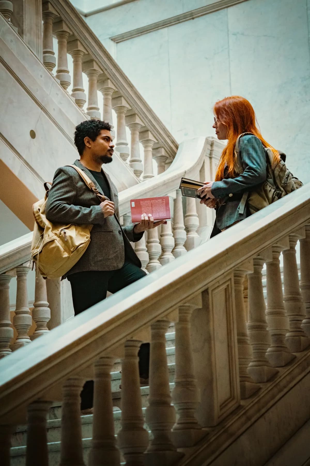Zwei Studierende unterhalten sich auf einer Treppe in Berlin