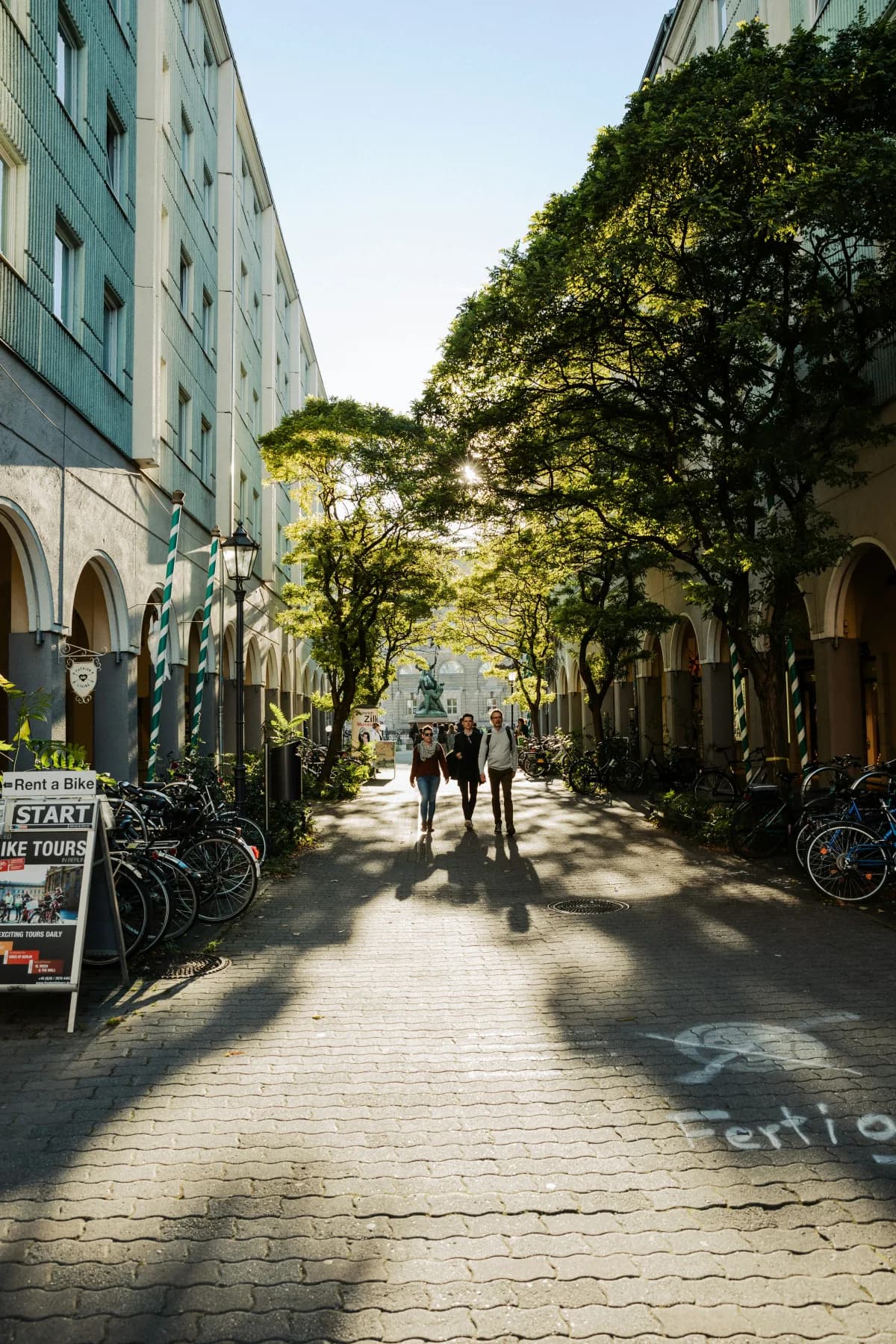 Travellers walking through a sunlit Berlin courtyard