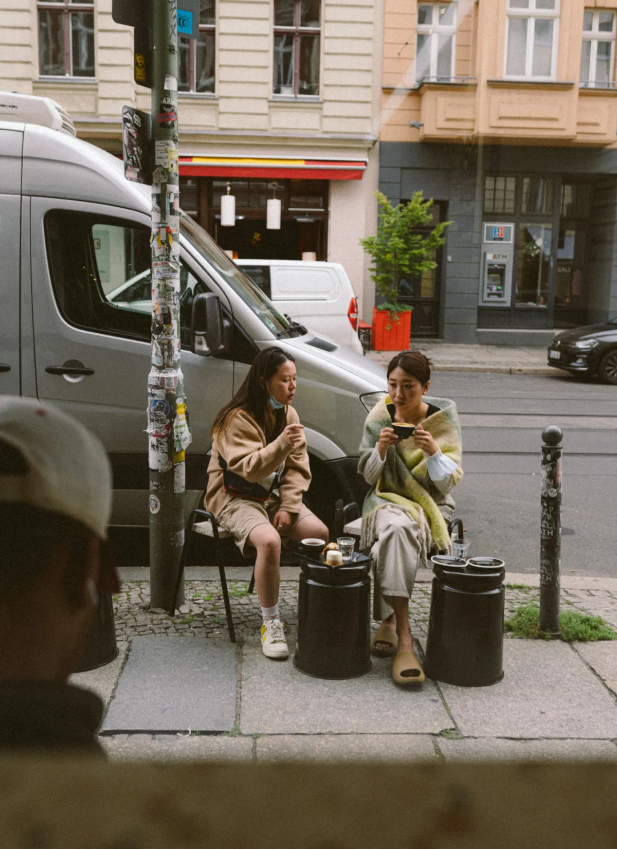 Two friends sharing coffee on a Berlin street