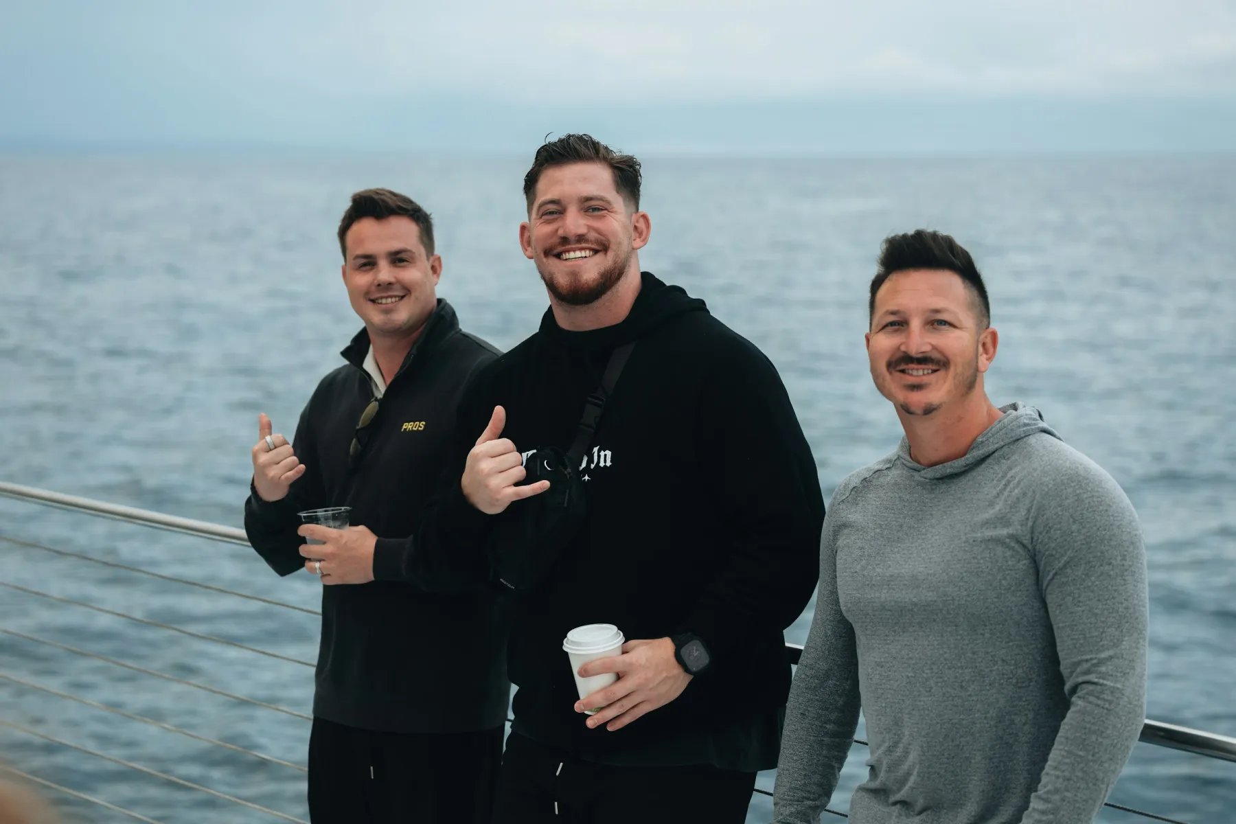 Three friends smiling together by the water